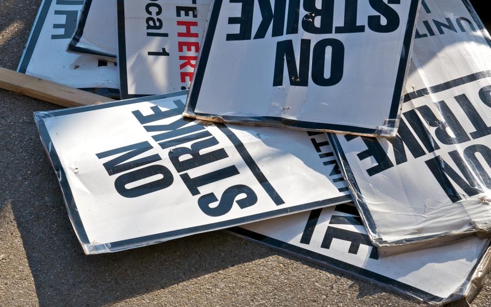 A bunch of "On Strike" signs on the ground after a protest.