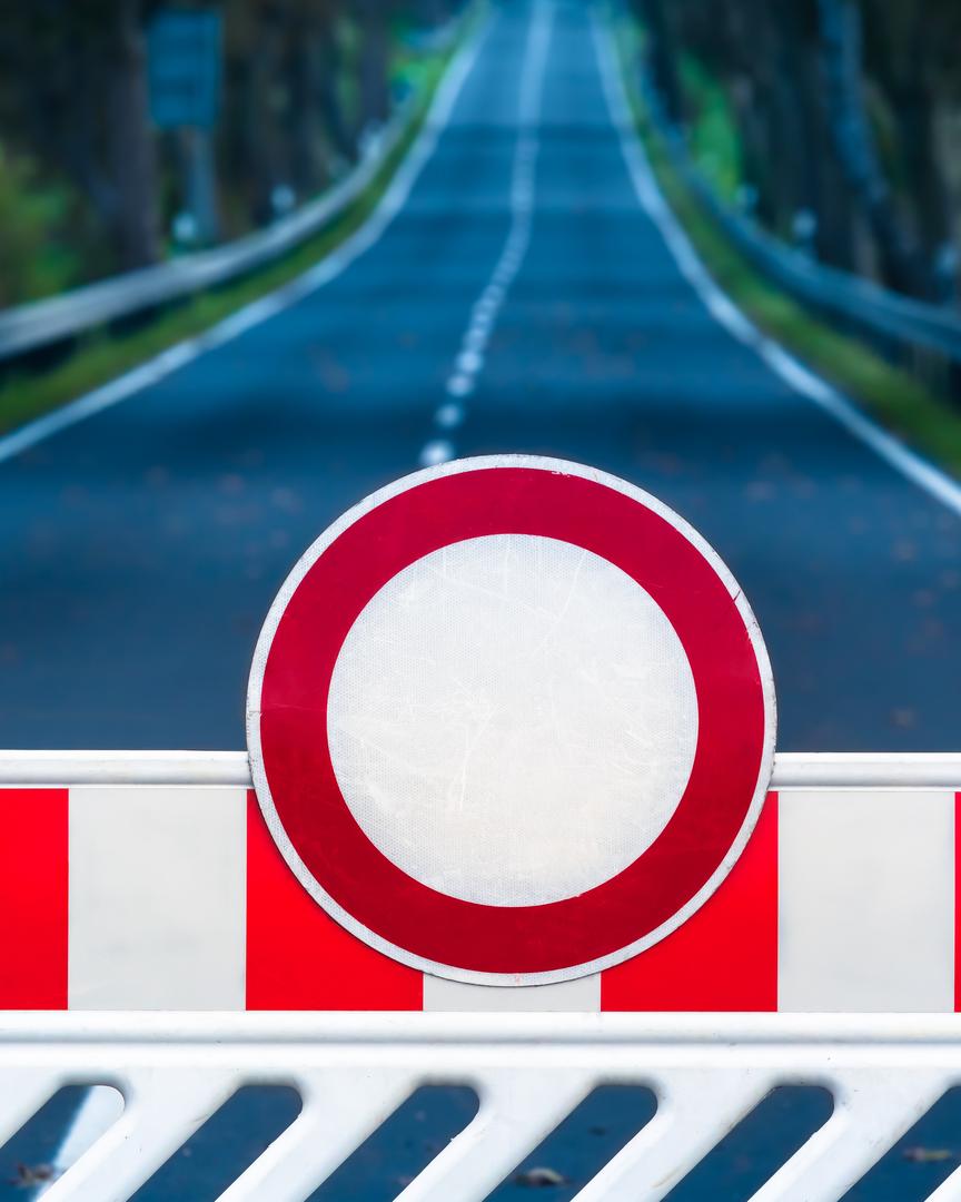 Red and white colored street barrier blocking an empty road.