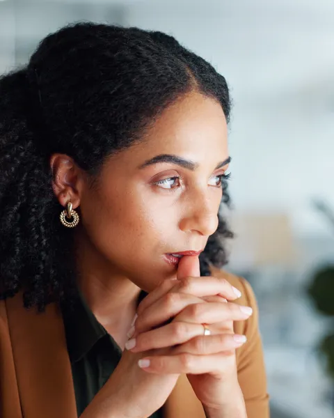 Woman at computer in office, thinking.