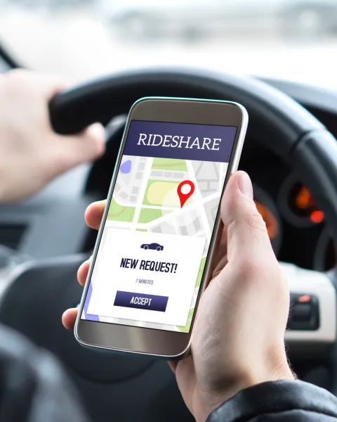 Ride share driver in car using the rideshare app in mobile phone.