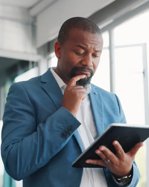 Close-up of a businessman, looking at a tablet in his hands, with a puzzled look on his face.