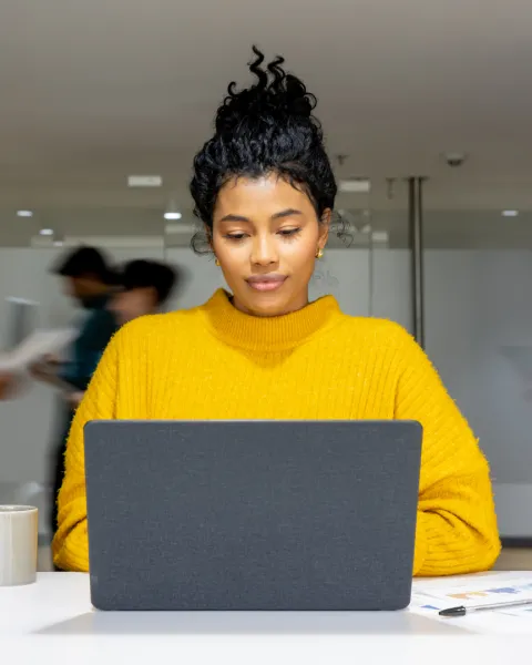  Businesswoman working on her laptop at a busy office.