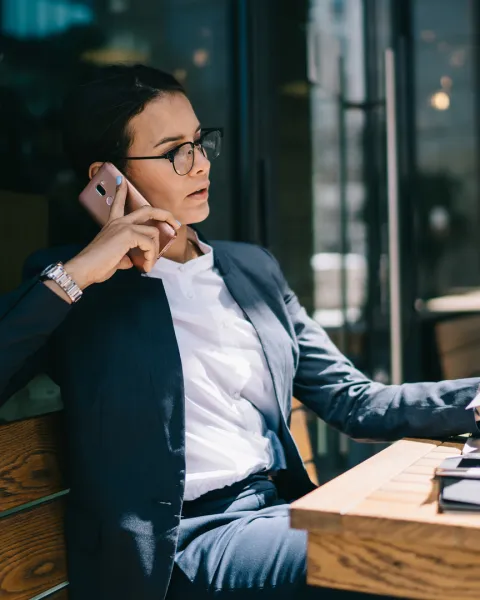 Busy businesswoman calling on mobile phone during remote work.
