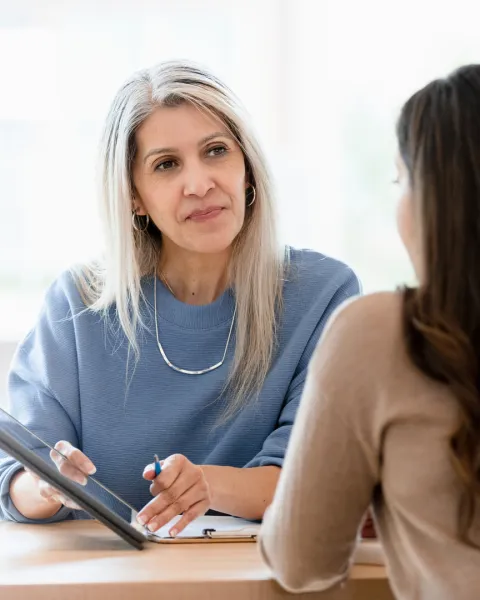 A femail manager having a discussion with a female employee while referencing something on a tablet.