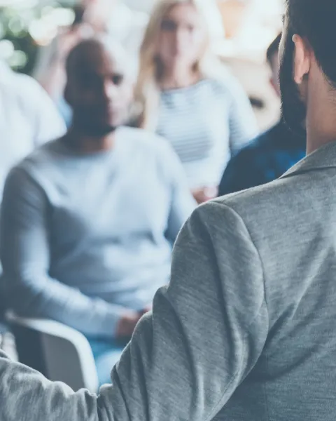 A manager up in front of an audience of employees, giving a lecture.