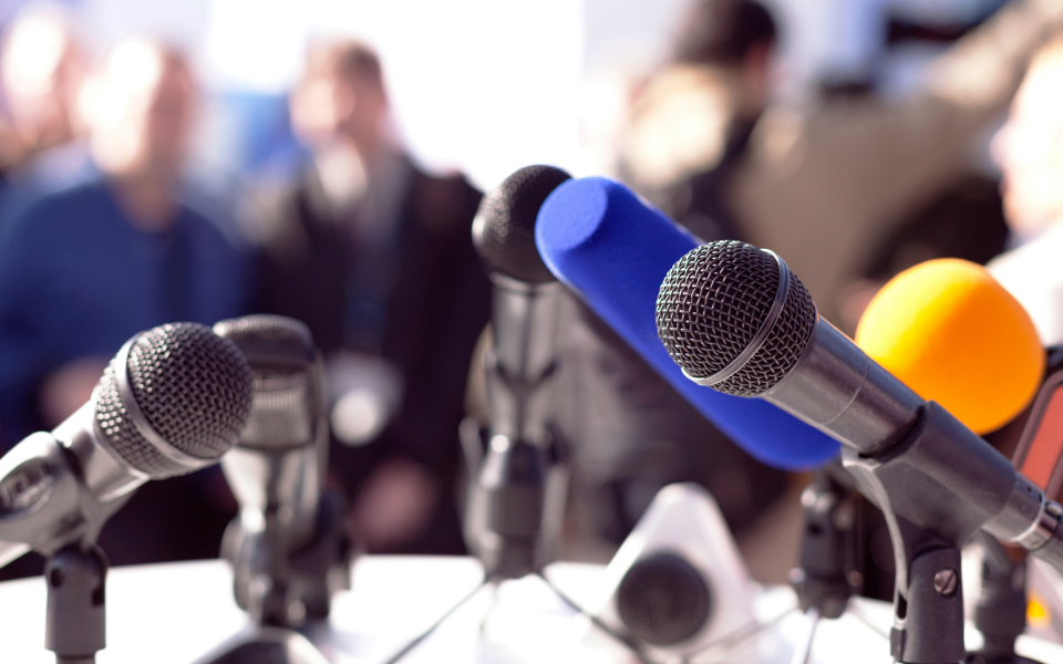 Table with microphones set up for a press conference