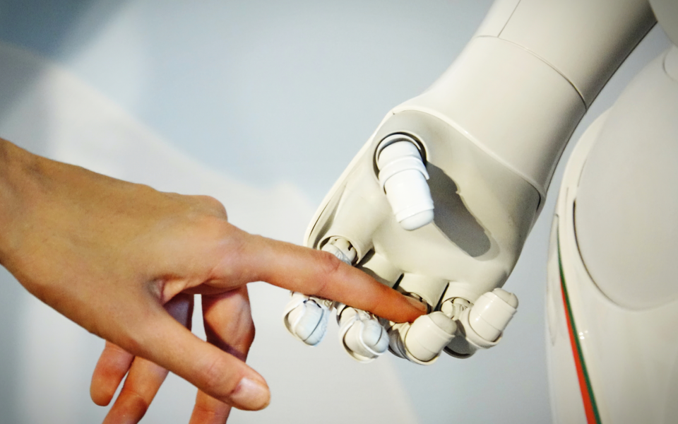Close-up of a human hand touching a robot hand
