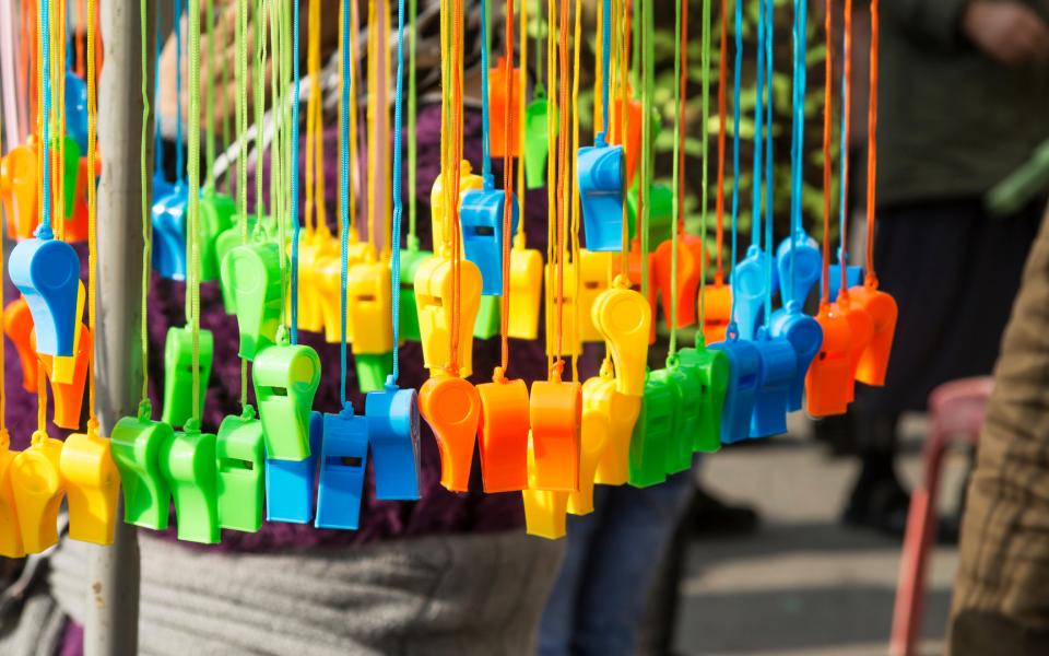 Many multi-colored toy whistles hanging on display.