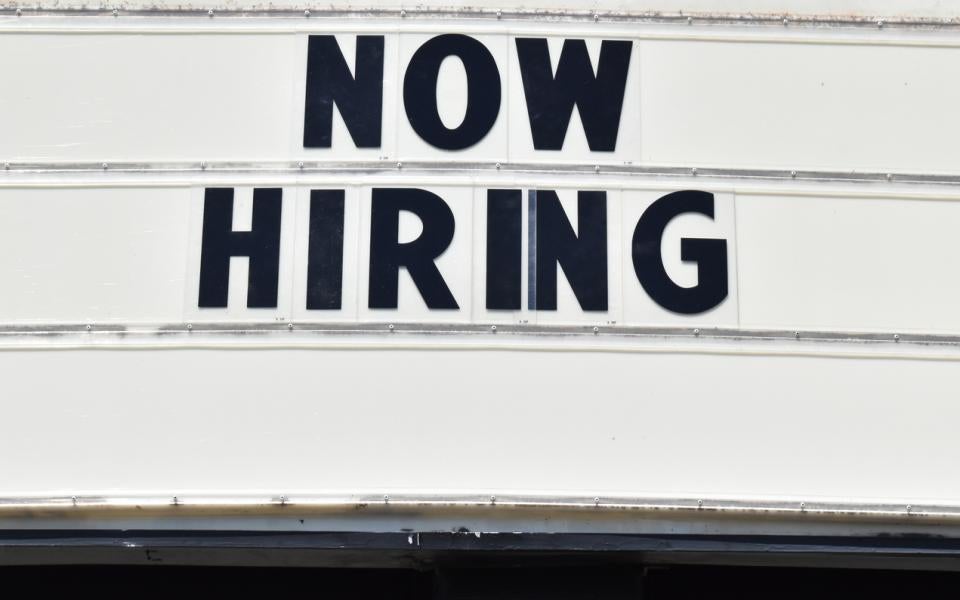 A theater marquee displaying the words, "Now Hiring".