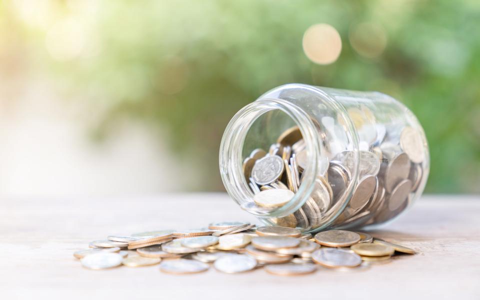 A tipped glass jar of coins.