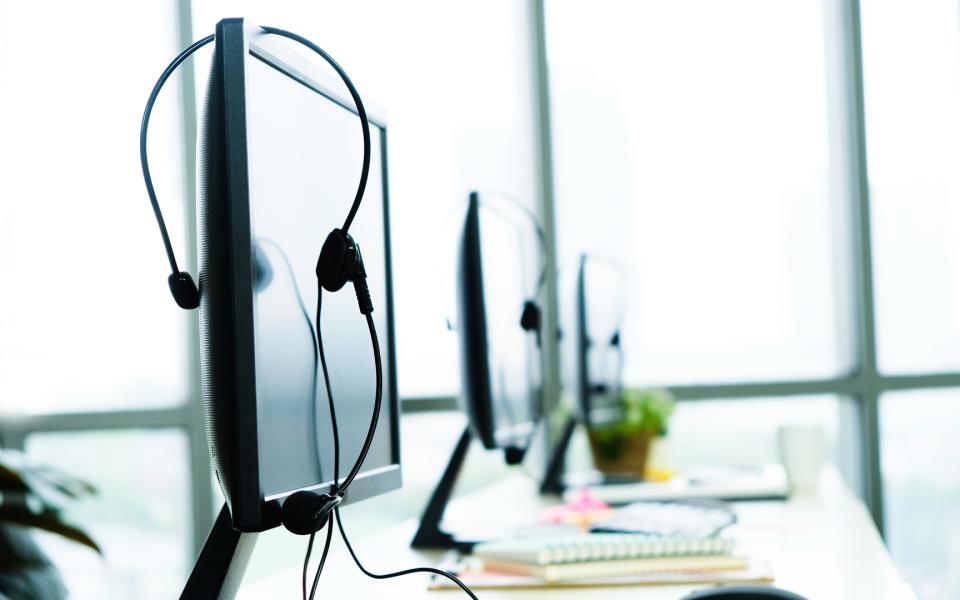 A view of an empty call center with monitors and headphones.