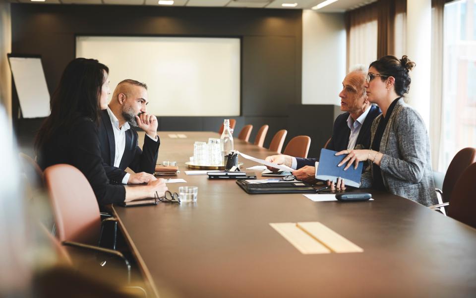 A group of people sitting at a conference room table discussing a matter.