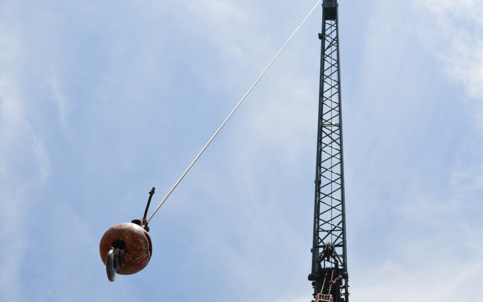 Image of a crane and a swinging wrecking ball.