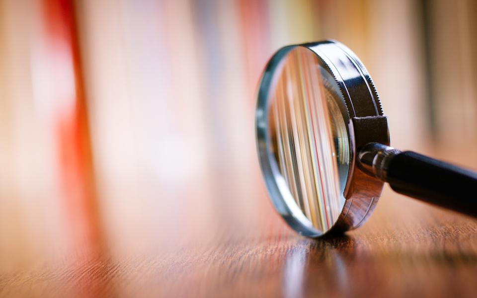 Magnifying glass sitting on its side on a wooden table.