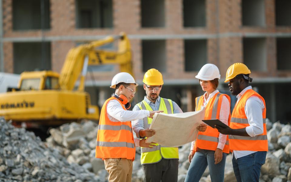 A diverse team of construction workers on a job site looking at plans.