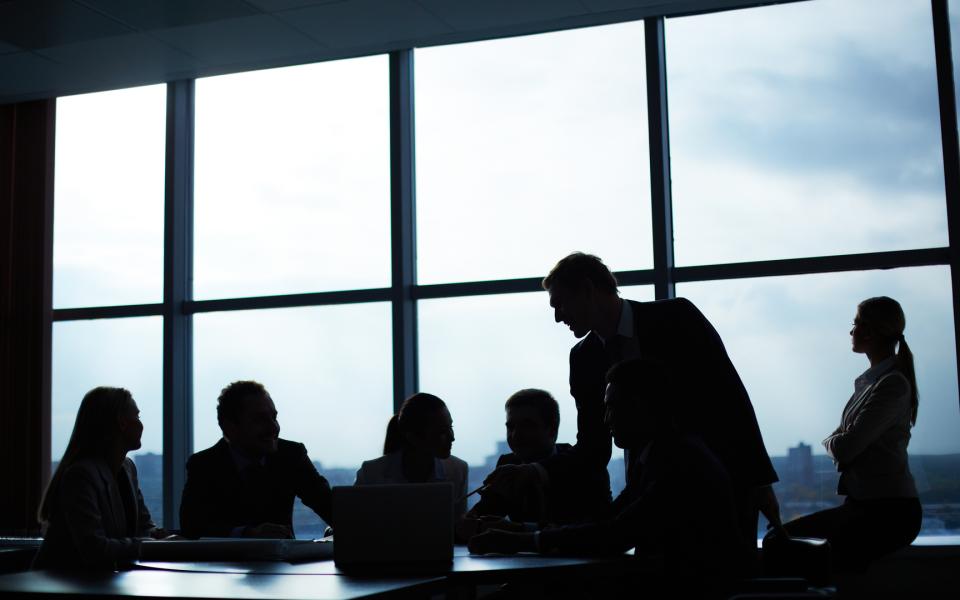 Silhouetted people in a conference room in discussion.;