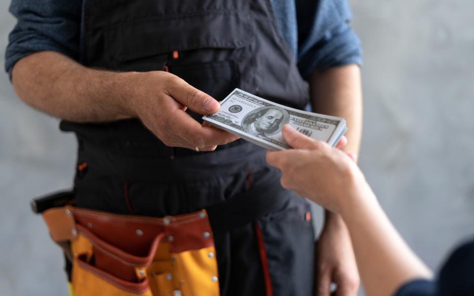 A hand giving money to a construction worker.