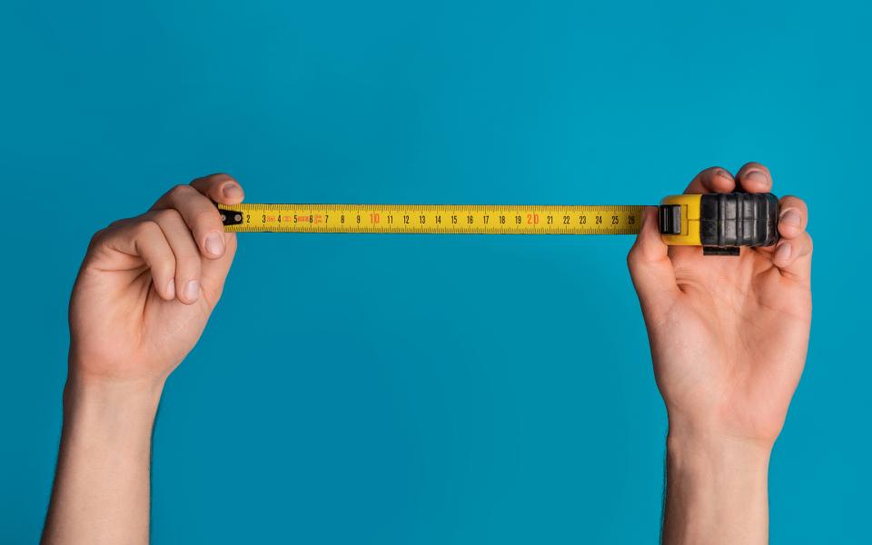 Two hands pulling and expanding a tape measure.