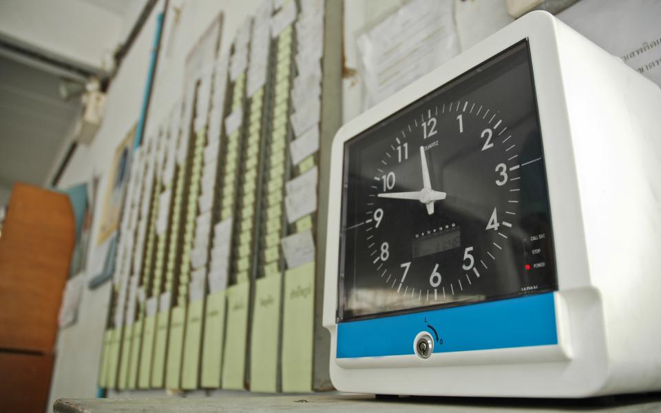 A photo of a time clock and a wall of timecards/punchcards.