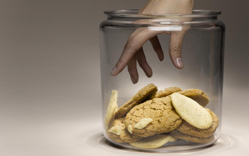 Close-up of hand reaching for cookies in cookie jar.