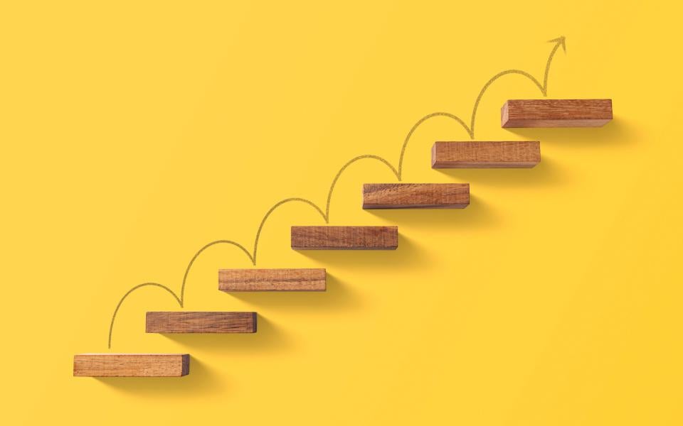 Wooden blocks arranged in a shape of staircase with an arrow climbing up.