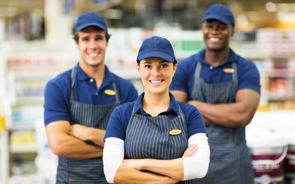 A trip of retail employees in aprons, caps and name tags.