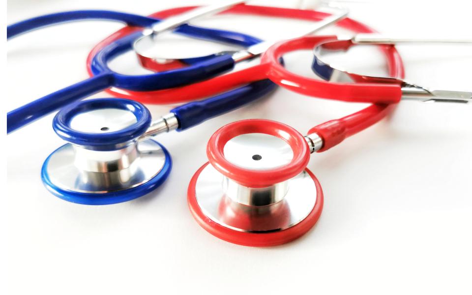 Close up view of two tangled stethoscopes on white background.