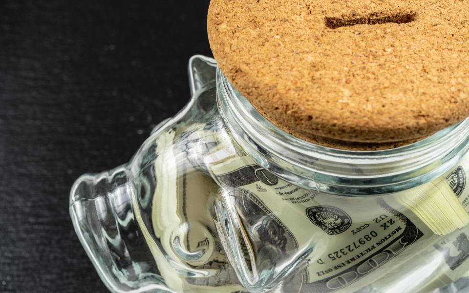 Close-up of top of glass piggy bank filled with money.