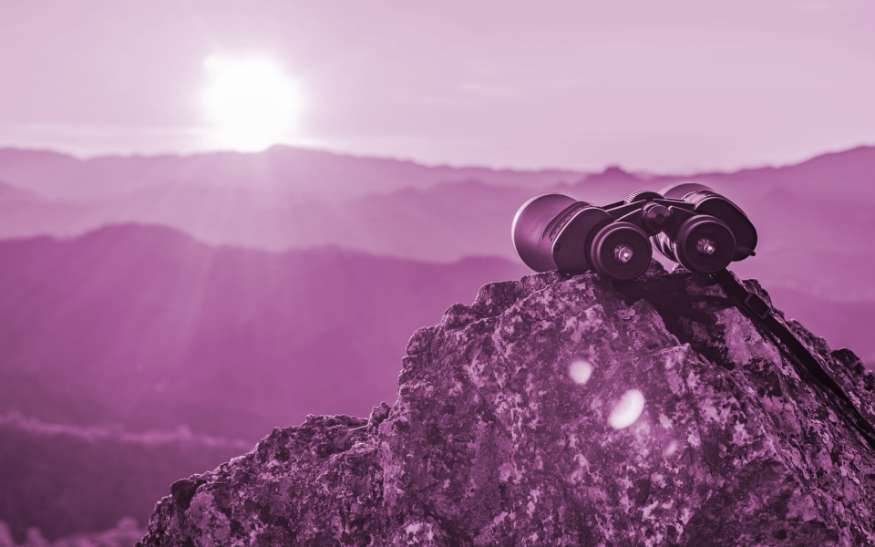 Binoculars on top of rock mountain at beautiful sunset background.