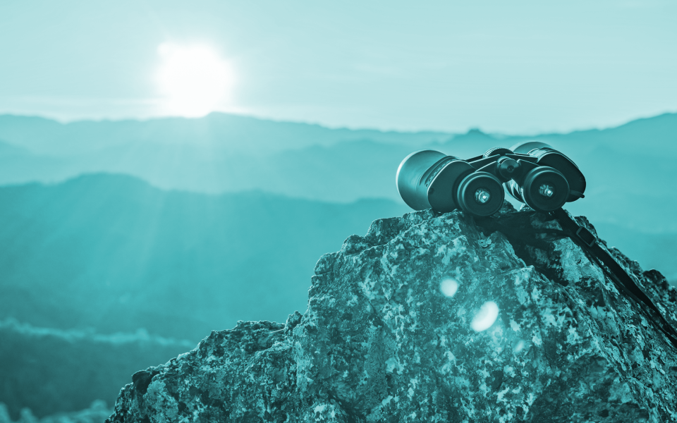 Binoculars on top of rock mountain at beautiful sunset background.