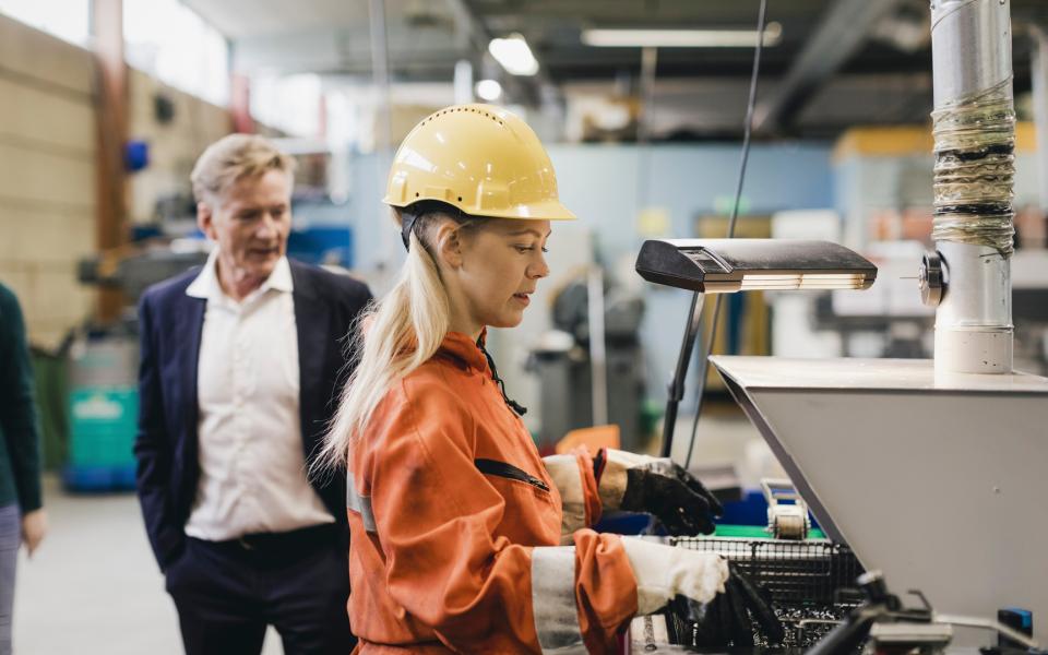 A supervisor looks over the work of a manufacturing employee.