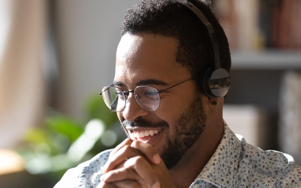 A man wearing headphones listening to a podcast on a computer.