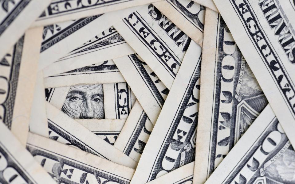 A stack of dollar bills, formed in a circle, like a shaft, with George Washington's face peeking out at the bottom.