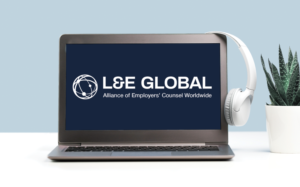 Laptop with headset hanging on it with the L&E Global logo on the screen.