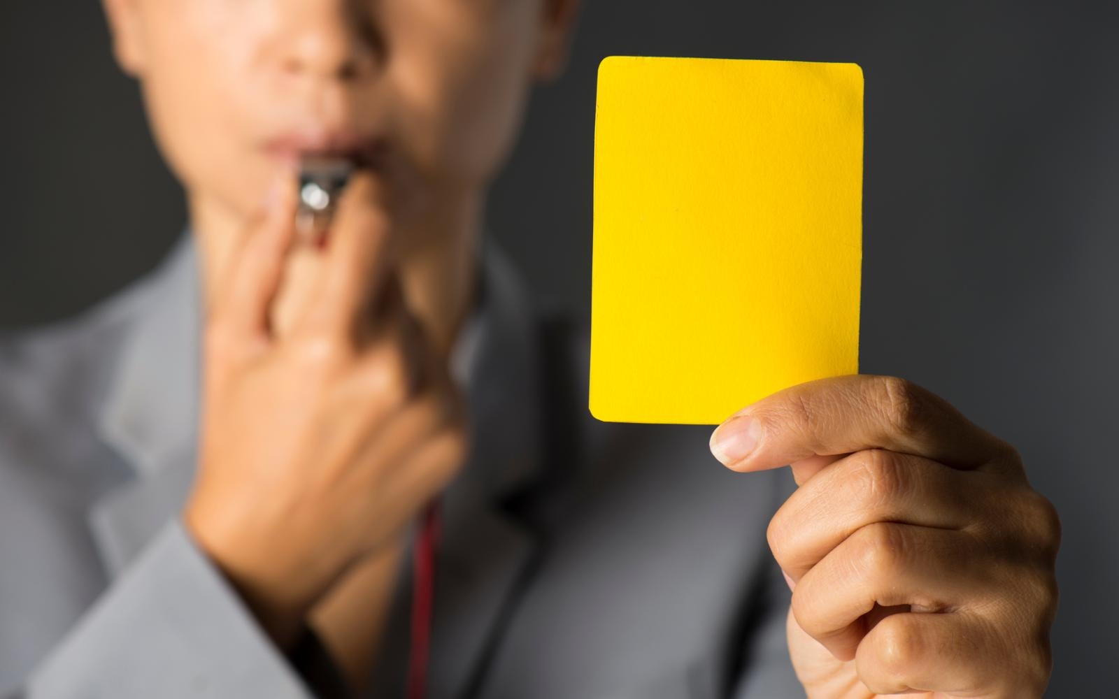 Business woman holding yellow card and blowing a whistle.