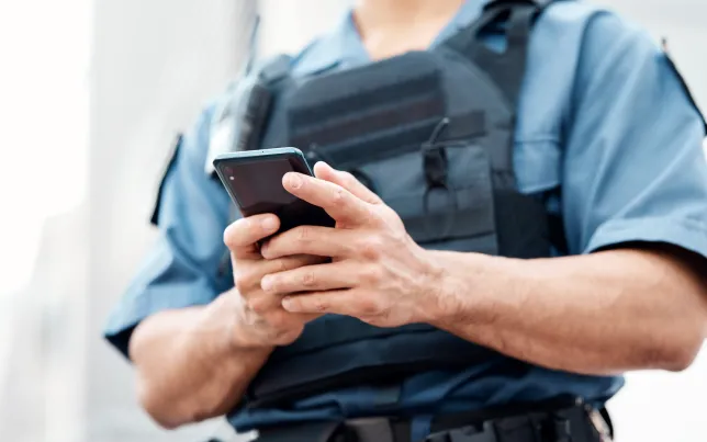 close up of a law enforcement officer's hands looking at a smartphone.
