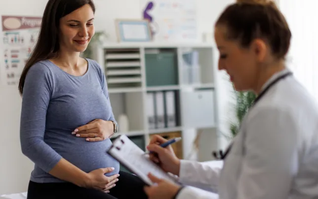 hot of a female doctor going over paperwork with a pregnant patient.