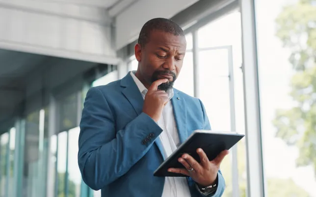 Close-up of a businessman, looking at a tablet in his hands, with a puzzled look on his face.