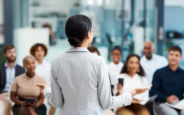 A view from behind a woman presenting to, or training, a team of employees.