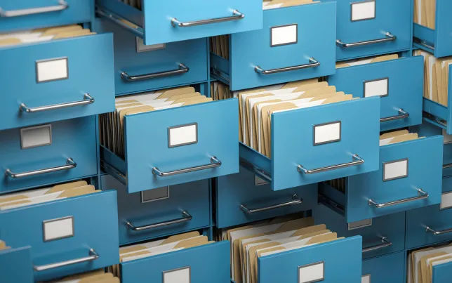 An image of many open file cabinet drawers stuffed with folders and paperwork.