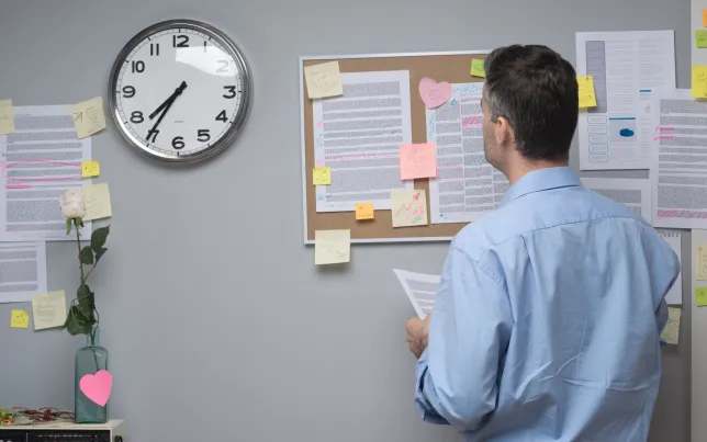 Office worker checking notes/notices on a bulletin board.