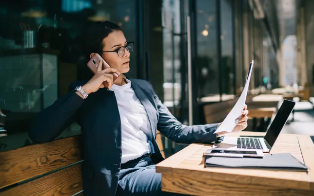 Busy businesswoman calling on mobile phone during remote work.