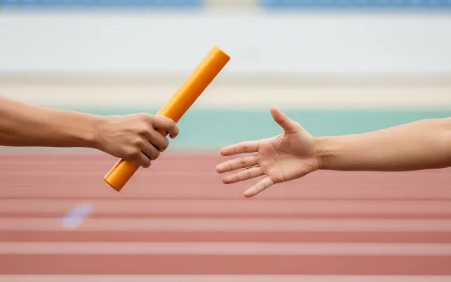 Close-up of a relay race baton exchange on a track between two athletes.