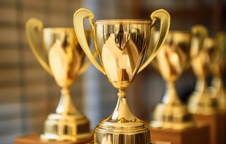 A close-up of a grouping of multiple gold trophies.